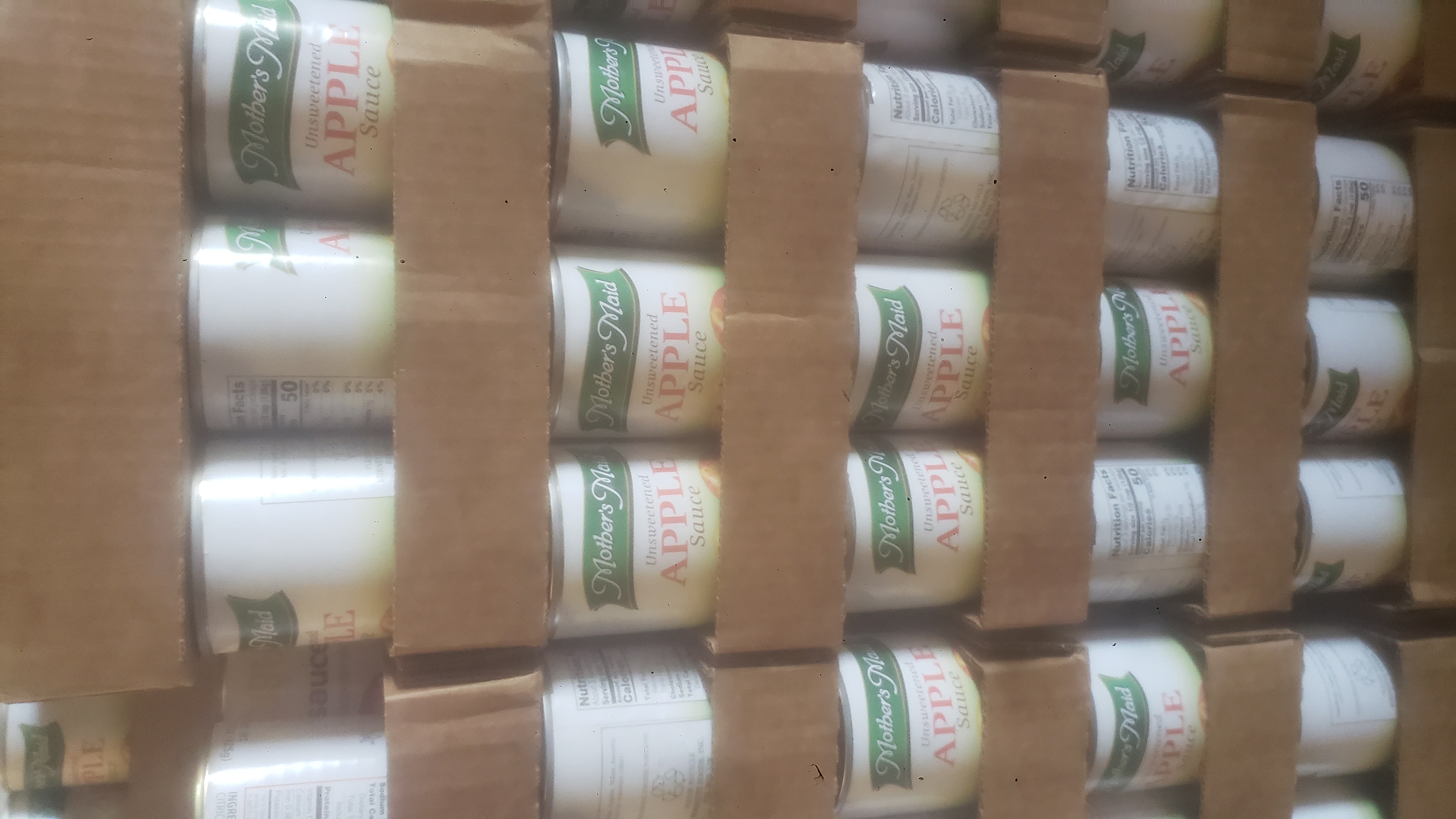 Stacks of canned apple sauce on cardboard trays.